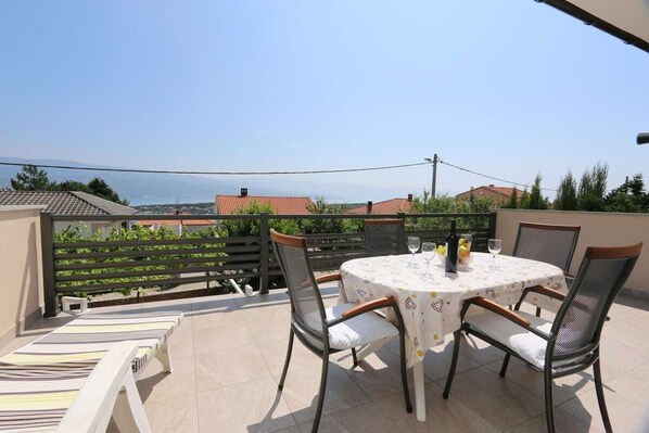 Une terrasse avec une table ronde, des chaises et une vue sur la mer.