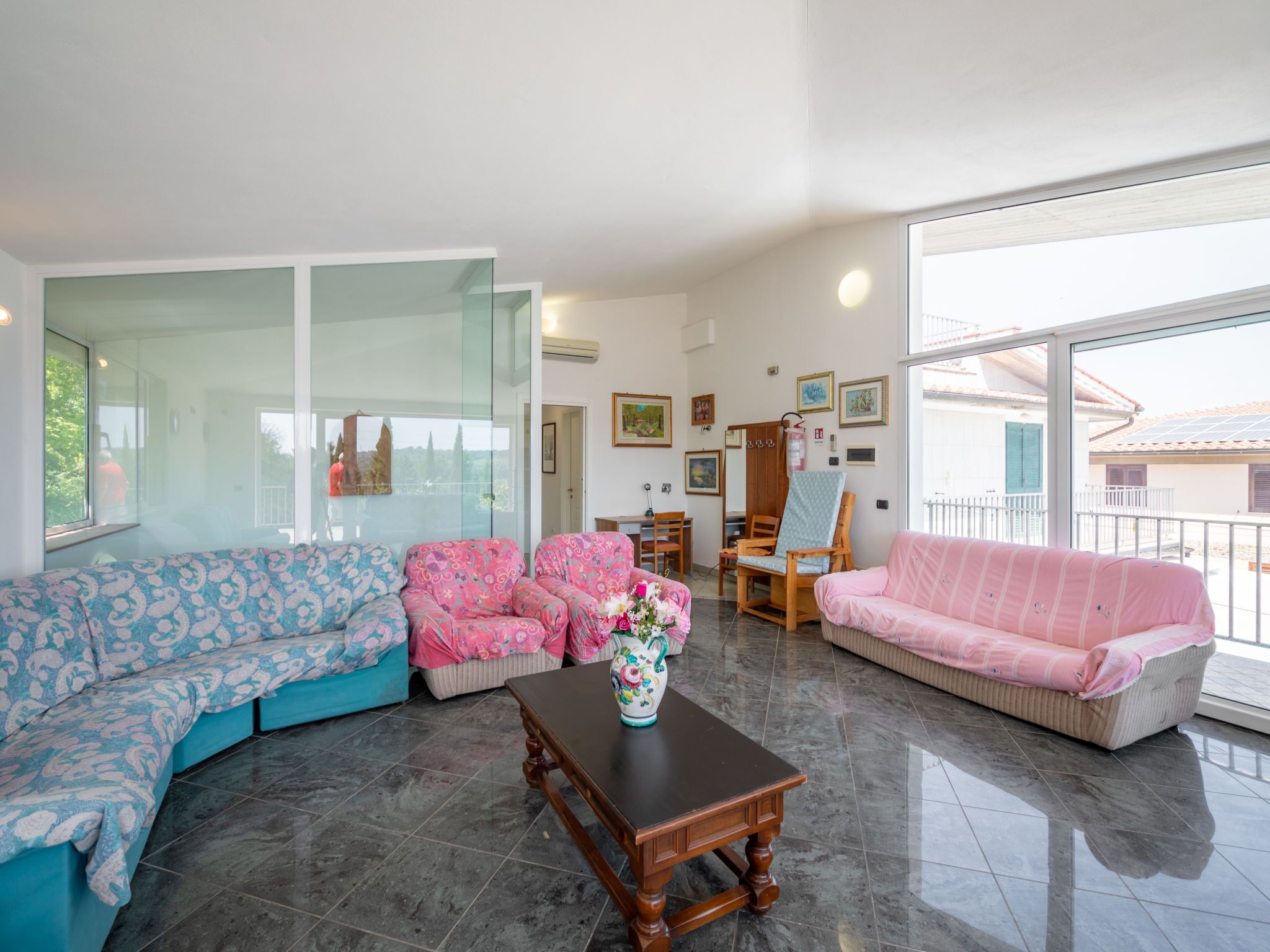 A spacious living room with a large window, two sofas, a wooden coffee table, and a dining area.