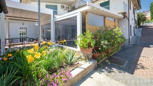 Une maison moderne dotée d’un patio couvert, d’un jardin fleuri et d’un chemin en briques.