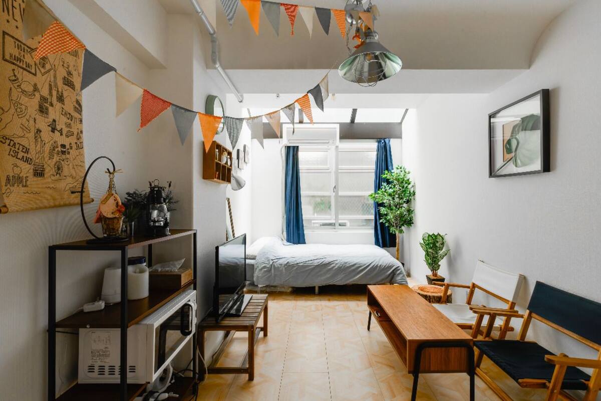 Una habitación acogedora con una cama, un escritorio, una silla, una mesa, una planta en maceta y un televisor.