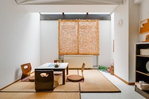 Une pièce avec des tatamis, une petite table sur laquelle est posée une plante, et une porte coulissante de style japonais traditionnel.