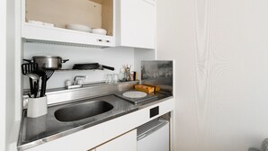 A modern kitchen with a double sink, stainless steel appliances, and white cabinetry. - Imperial-Semba (Osaka)