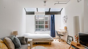 A modern bedroom with a bed, a desk, a TV, and a skylight. - Imperial-Semba (Osaka)