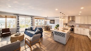 A spacious living area with a sofa, chairs, and a dining table. A kitchen with modern appliances and cabinets is visible. - Mar Azul \ Walk to the Beach \  Enjoy Ocean Views \  Near Newport (Middletown)
