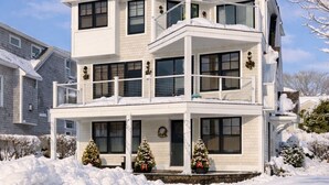 A two-story house with a balcony, surrounded by snow. - Mar Azul \ Walk to the Beach \  Enjoy Ocean Views \  Near Newport (Middletown)