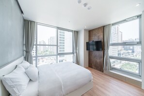A modern hotel room with a large bed, a flat-screen TV mounted on a wooden panel, and large windows offering a city view. - JUST SLEEP HOTEL No.2 (Gimpo)