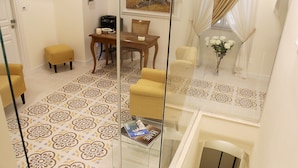 A hotel room with a dining area, a sofa, a glass coffee table, and a decorative vase with flowers. - Estlevante B&B (Vieste)