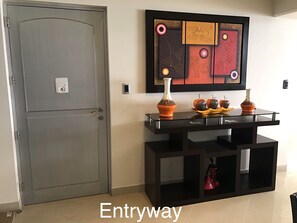 An entryway with a grey door, a black console table with decorative items, and a colorful abstract painting on the wall. - 15th_16th Floor Duplex-A_C & Spectacular Ocean Views Across from Parque del Amor (Miraflores)
