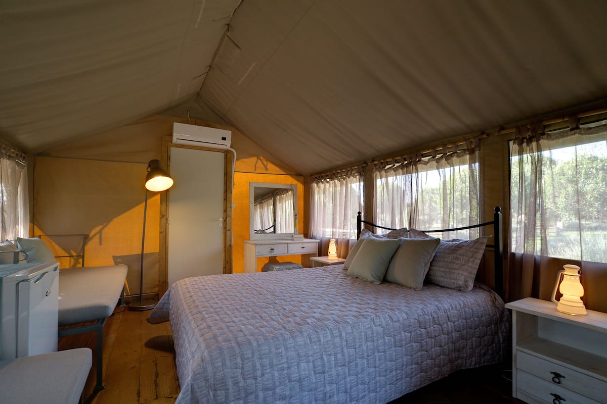 A bedroom with a bed, a dresser, a mirror, a desk, and a lamp.