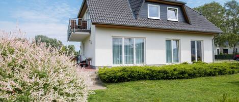 Ein modernes, zweistöckiges Haus mit einem geneigten Dach, einem Balkon und großen Fenstern.