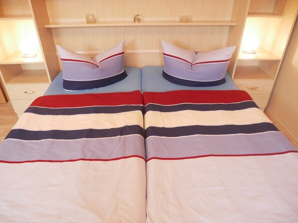 Un letto matrimoniale con biancheria a righe e cuscini coordinati, affiancato da comodini con lampade.
