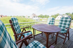 Una terrazza con sedie e tavolo di legno, con vista su una zona residenziale con case e vegetazione.