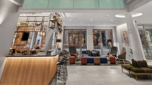Un interior de varios niveles con un espacio central abierto, barandillas de cristal y una zona de bar.