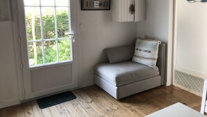 A small room with a door, a window, a sofa, a cabinet, and a wall-mounted picture. - La Cabane de pêche de la Cotinière (Saint-Pierre-d´Oléron)