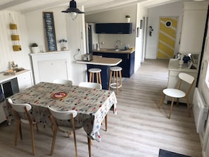 A compact kitchen with a dining area, wooden flooring, and a small island.