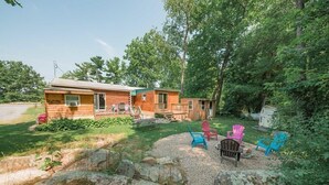 A cabin with a front porch, a small deck, and a gravel area with Adirondack chairs. - Super Clean, Pet Friendly Cottage! 3 Bedroom! NO EXTRA FEES!! (Alexandria Bay)