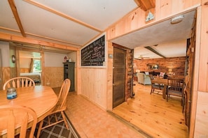 A wooden cabin interior with a dining area, a kitchen, and a living space. - Super Clean, Pet Friendly Cottage! 3 Bedroom! NO EXTRA FEES!! (Alexandria Bay)