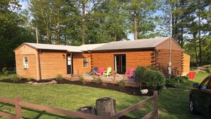 A log cabin with a porch, outdoor seating, and a fenced yard. - Super Clean, Pet Friendly Cottage! 3 Bedroom! NO EXTRA FEES!! (Alexandria Bay)