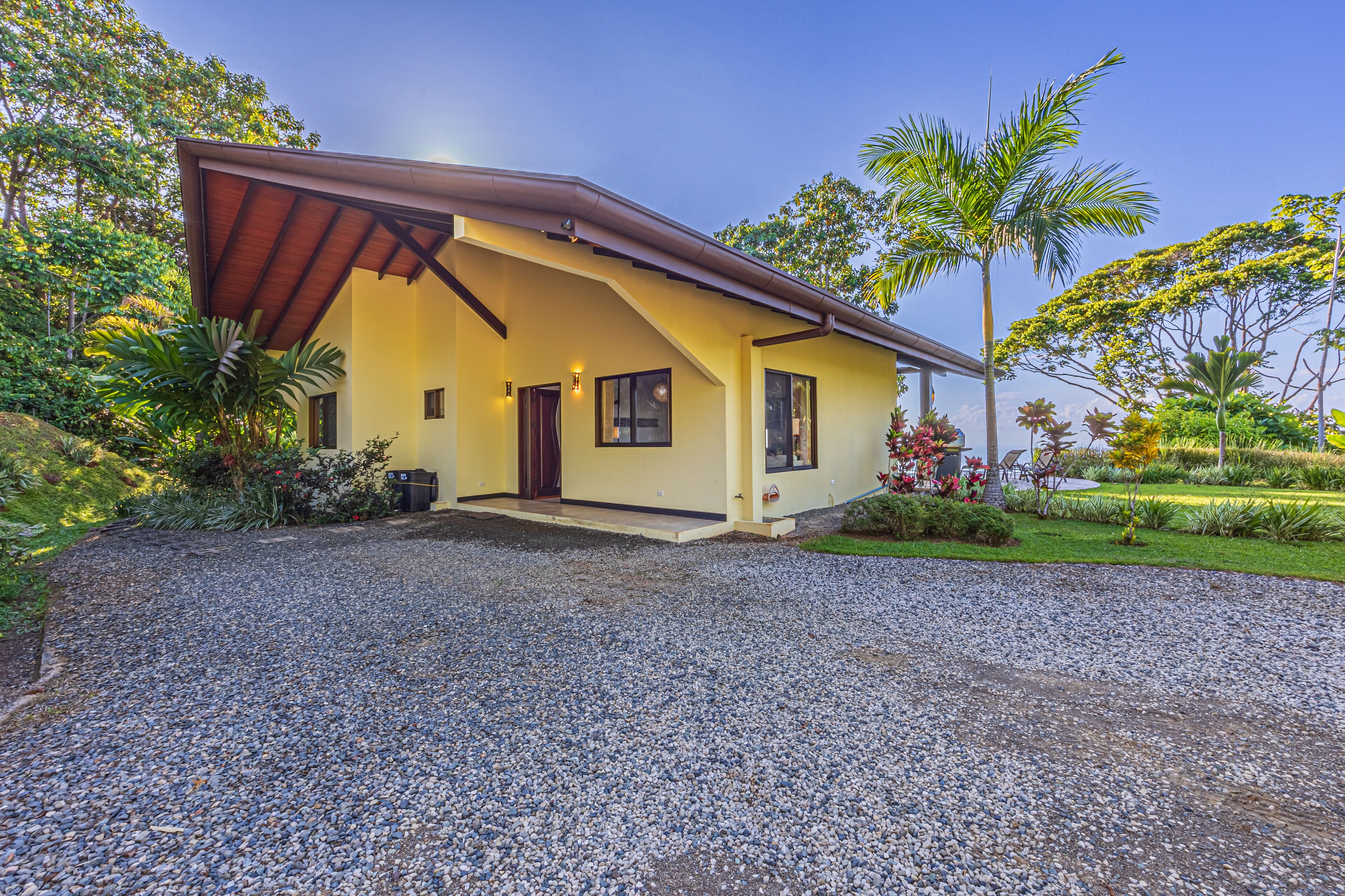 A house with a sloped roof, a front porch, and a gravel driveway.