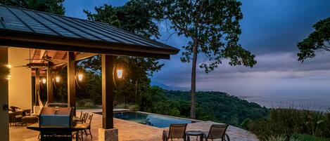 A covered outdoor area with a pool, seating, and grilling equipment.