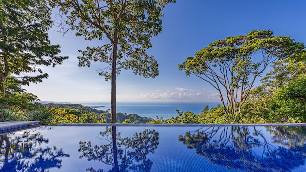 A clear view of a swimming pool with a tiled surface reflecting trees and a distant landscape.