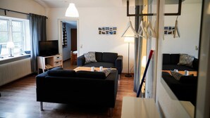 A modern living room with a sofa, a coffee table, a TV, and a lamp. - Vacation apartment Seeblick - Lindenhof (Steinberg)