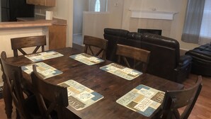A dining area with a wooden table and chairs, a black leather couch, and a kitchen area in the background. - Fetokai Suite Inn, this is a beautiful home and suites with your vacation (Arlington)