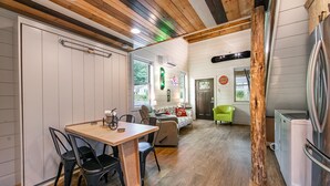 Eine gemütliche Küche mit Holztisch und -stühlen, einem Kühlschrank und einer Essecke mit einer Couch und einem Sessel.