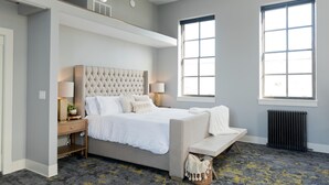 Un dormitorio moderno con una cama grande, mesitas de noche, un banco y un radiador.