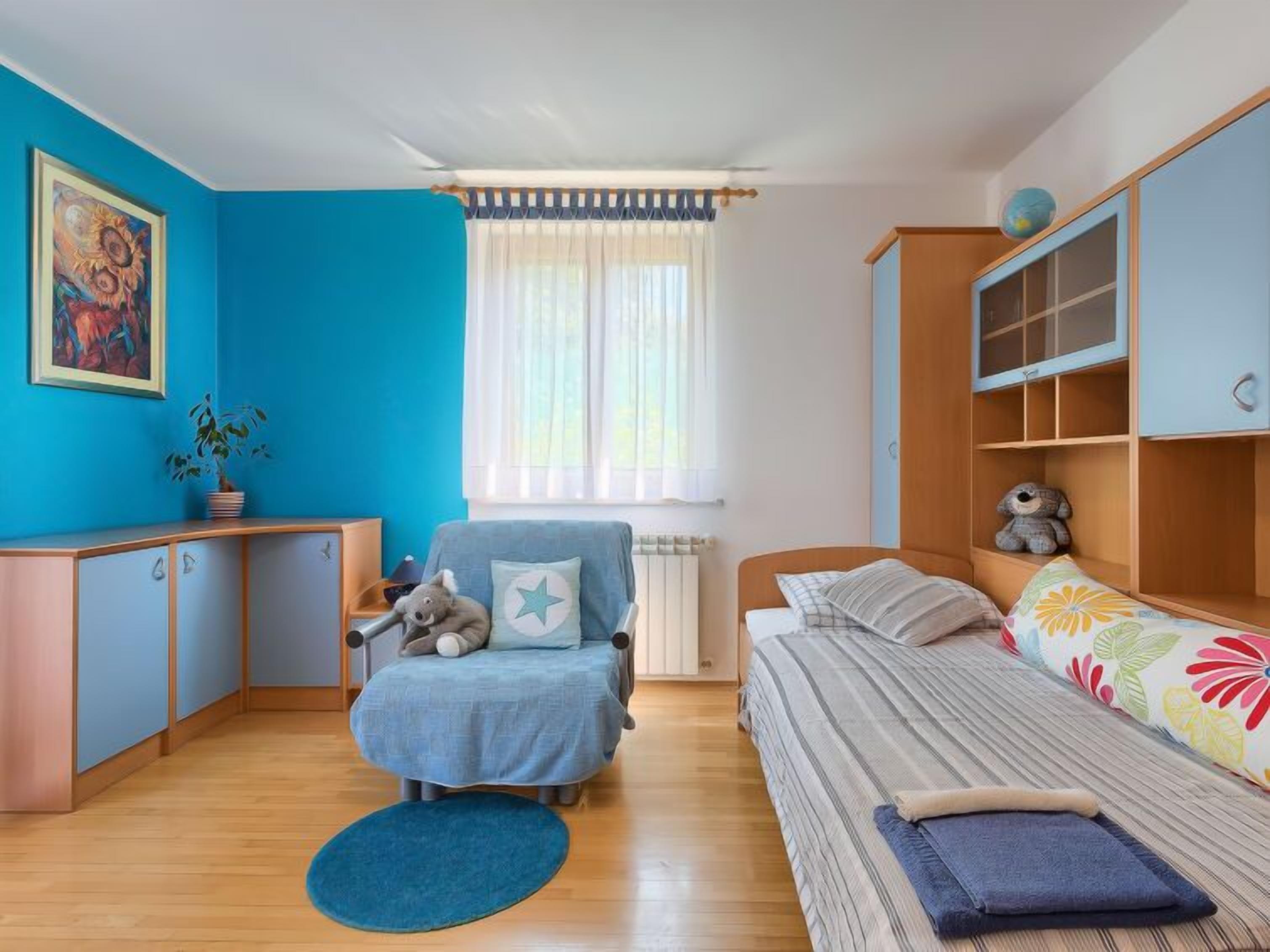 Une chambre d’enfant avec un lit, une chaise, un bureau et une bibliothèque.