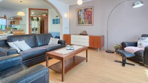 A modern living room with a sofa, a coffee table, and a desk. There is a painting on the wall and a lamp. - Vacation home Corina by Interhome (Medulin/Šišan)