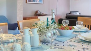 A dining area with a table set for two, featuring a floral centerpiece, a bottle, and a bowl of strawberries. - Vacation home Corina by Interhome (Medulin/Šišan)