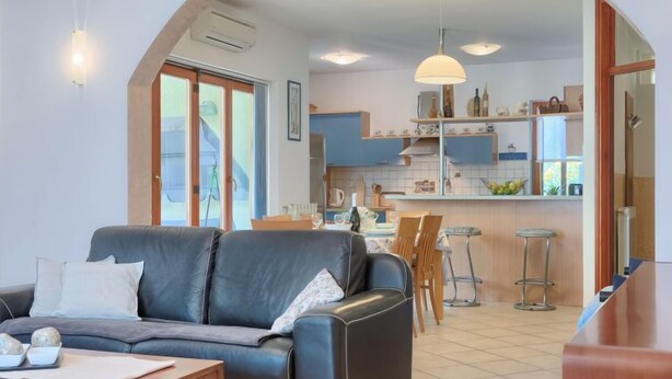 A modern living room with a sofa, a coffee table, and a dining area with chairs and a table. - Vacation home Corina by Interhome (Medulin/Šišan)
