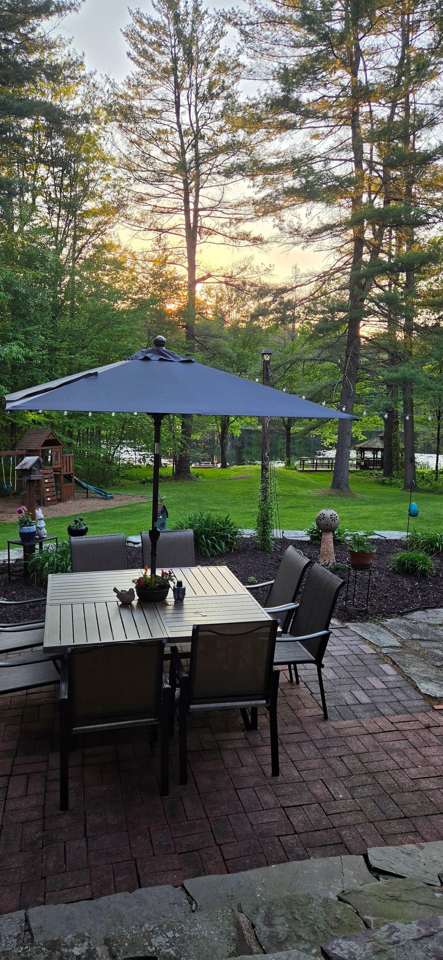 A patio with a table and chairs, surrounded by a garden and trees.