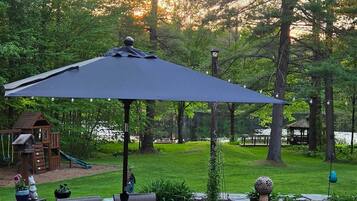 A patio with a table and chairs, surrounded by a garden and trees.