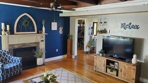 Un salon avec une cheminée, un téléviseur et un mur d’accent bleu.