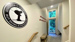 A hallway with a circular sign on the wall, a wooden bench, and a door leading to a garden.