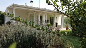Une maison moderne dotée d’un porche abrité, entourée d’une végétation luxuriante.