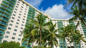 Un hôtel de grande hauteur doté de nombreux balcons et bordé de palmiers.