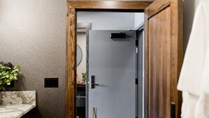 A modern bathroom with a geometric patterned wall, a wooden door frame, and a minimalist design.