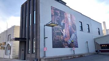 A building with a mural on its side, a sign prohibiting smoking, and a street lamp.