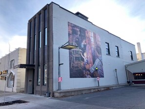 Un edificio con un mural en la pared, un cartel que prohíbe fumar y una farola.