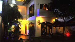 A two-story house with a balcony, a covered patio, and a well-lit entrance. - New York Guest House (Negombo)