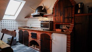 Una cocina con chimenea de ladrillo, horno moderno y una decoración con casco vikingo.