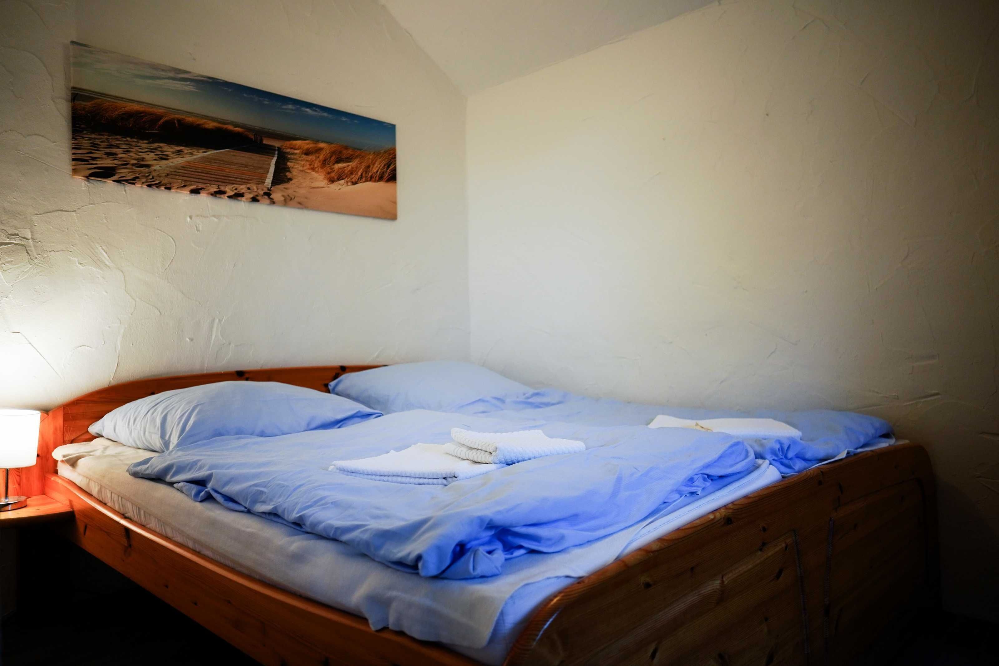 Una cama individual con cabecera de madera en una habitación con paredes blancas.