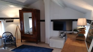A bedroom with a bed, a wooden dresser, a TV, a mirror, a chair, and a small table. - Oasi dei Vandali, small and cozy residence in the historic center, 5 min from the sea (Mondolfo)