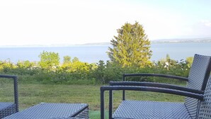 A patio with wicker chairs and a view of a body of water. - Littoral Lac (La Grande-Béroche)