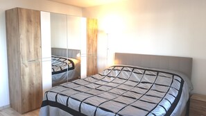 Un dormitorio con cama, armario y espejo.