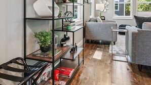 A modern living room with a black metal shelving unit, a grey sofa, and a wooden floor.