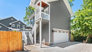 A two-story house with a covered porch, a garage, and a wooden fence.